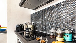 Una cucina moderna con una macchina per caffè, tazzine da caffè e un piatto di croissant.