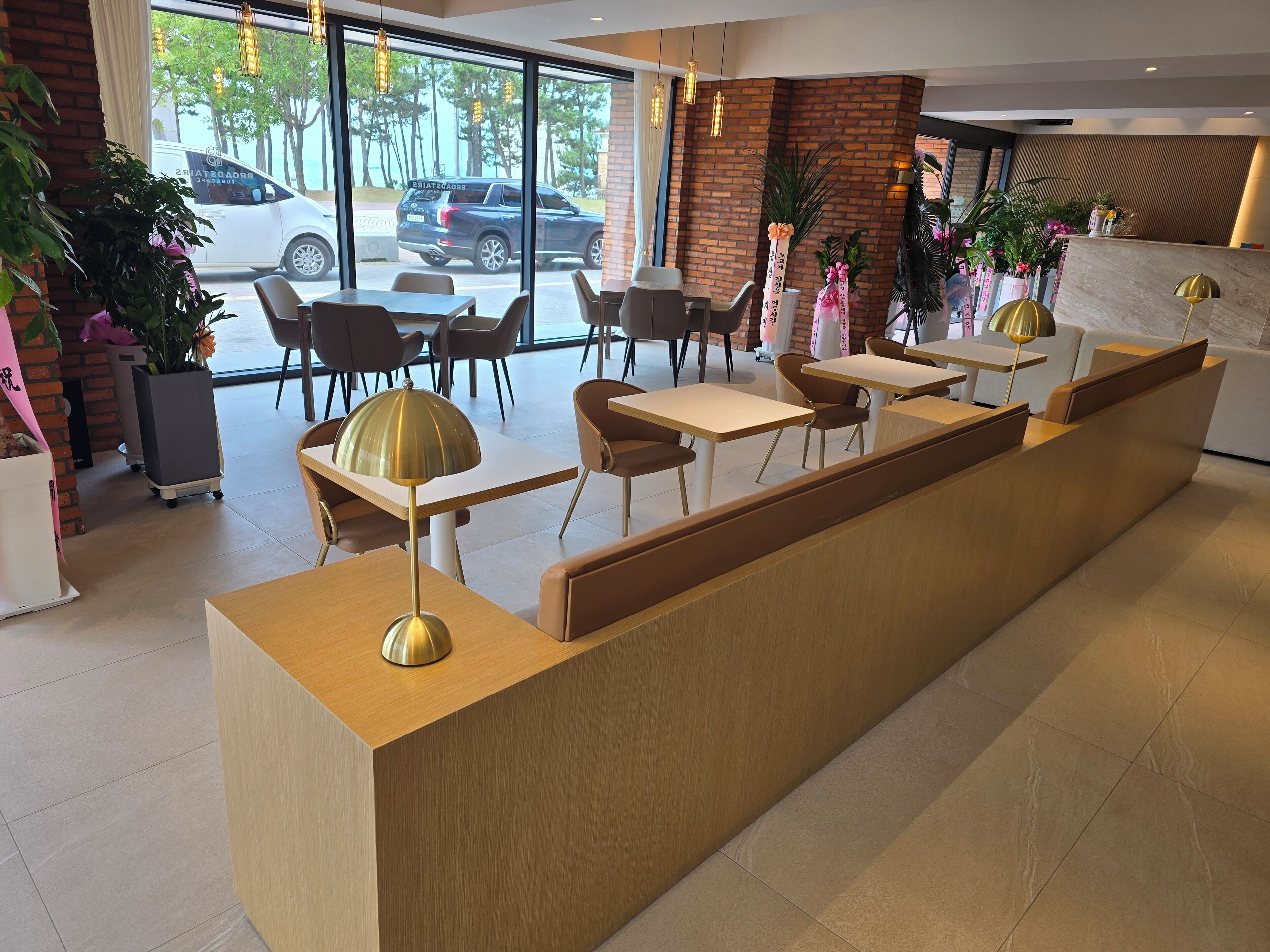 A modern reception area with a wooden reception desk, seating arrangements, and large windows offering a view of the street.