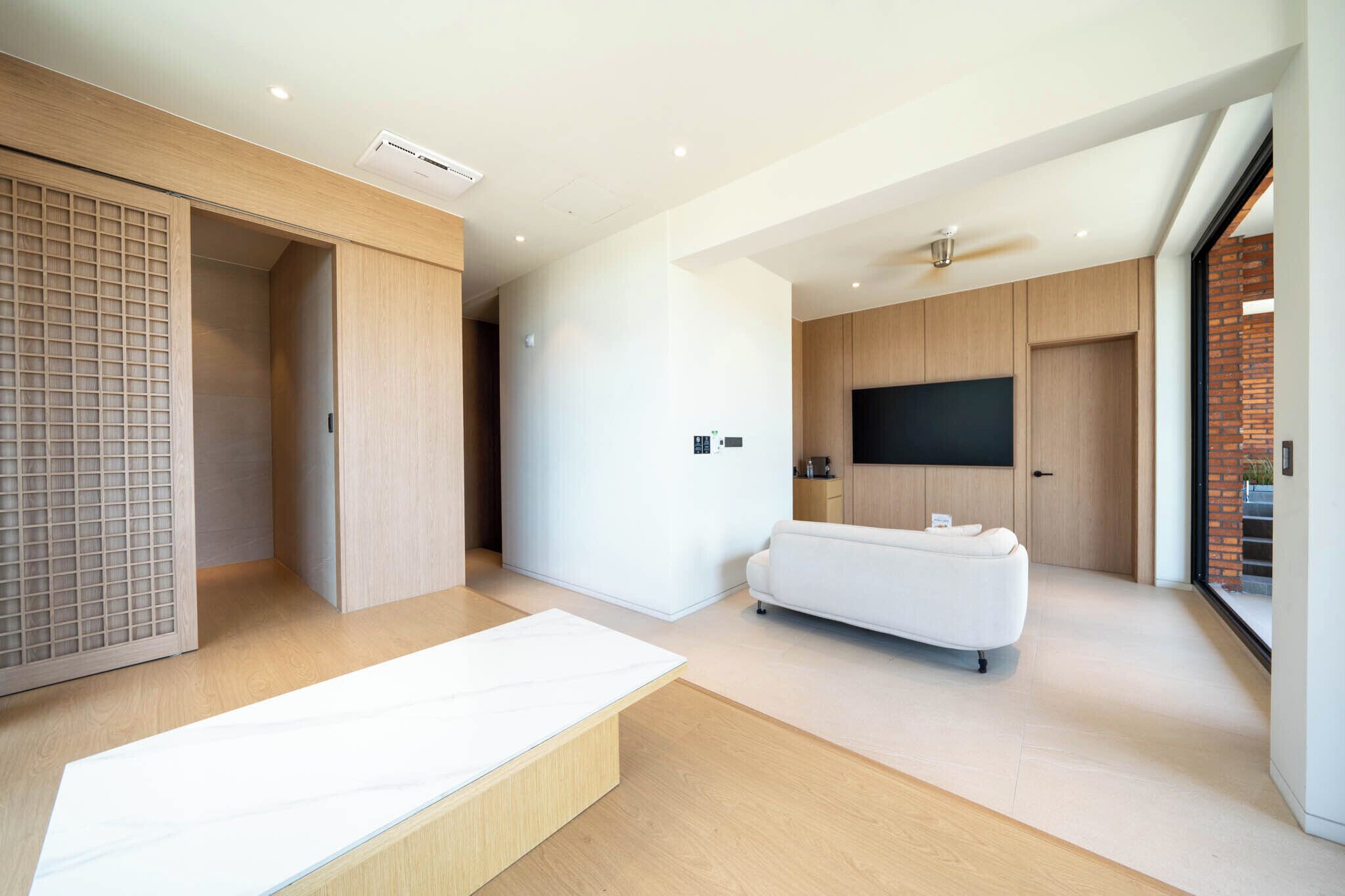 A modern living room with a sofa, a TV, and a sliding door.