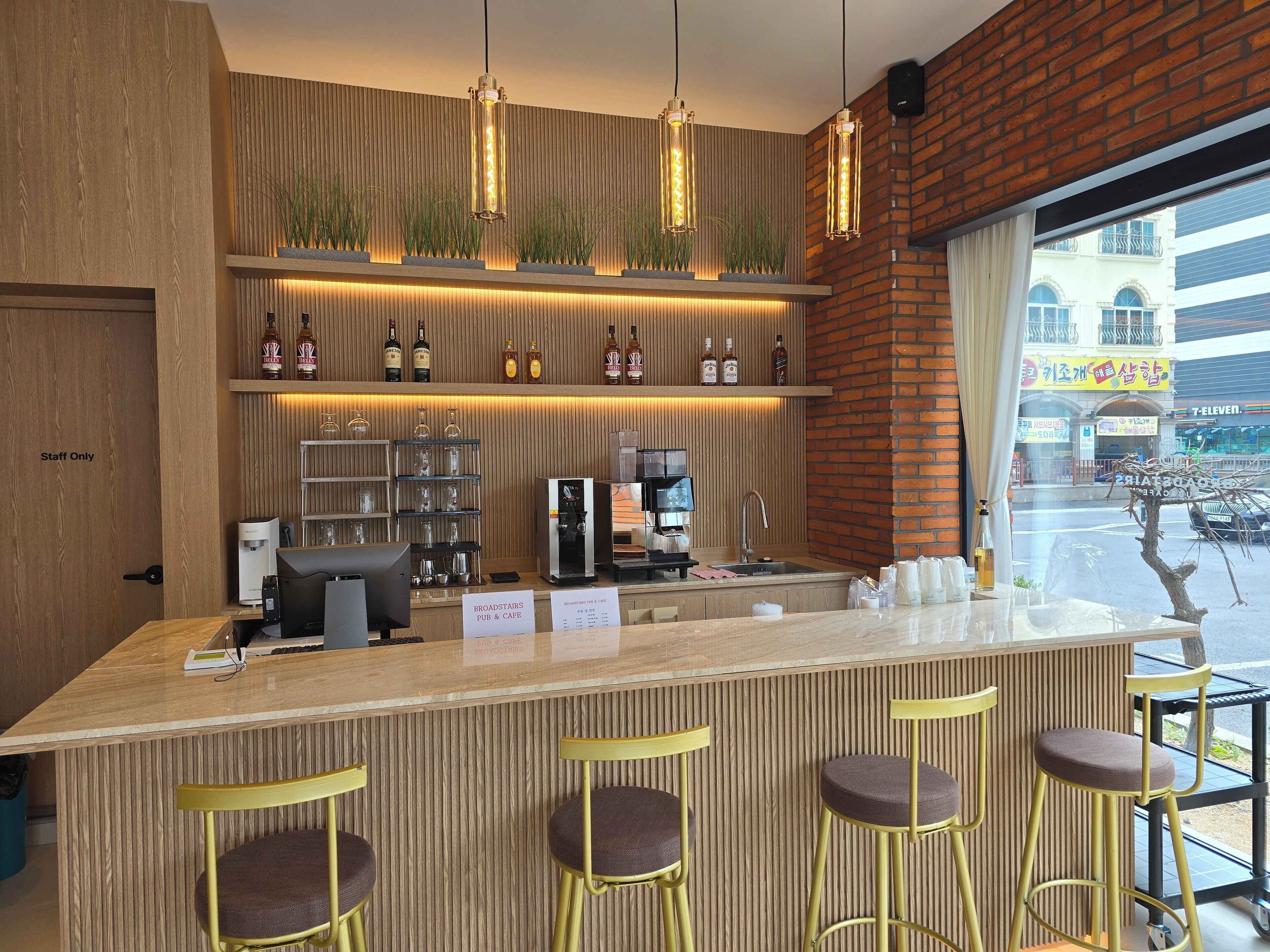A modern bar area with a wooden counter, bar stools, and a coffee machine.