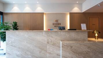 A hotel reception desk with a marble counter, a reception area with wooden paneling, and a 'Staff Only' door.
