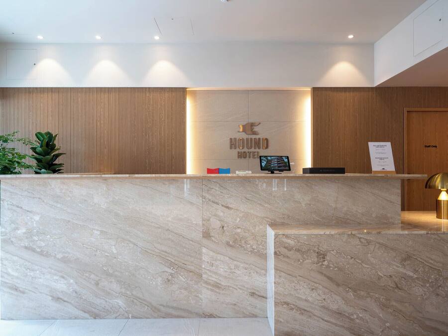 A hotel reception desk with a marble counter, a reception area with wooden paneling, and a 'Staff Only' door.
