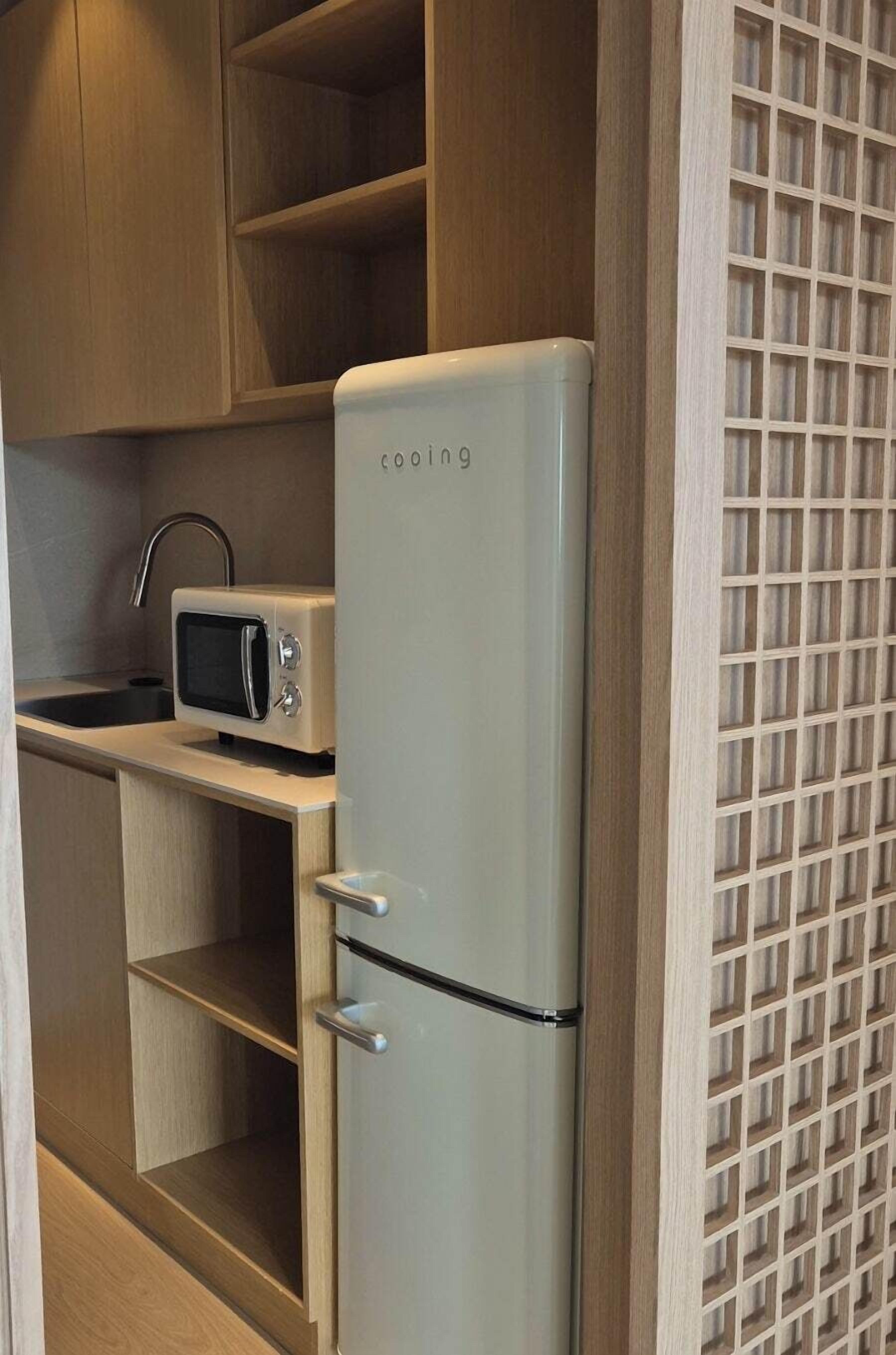A compact kitchen with a white refrigerator, a microwave, and wooden cabinets.