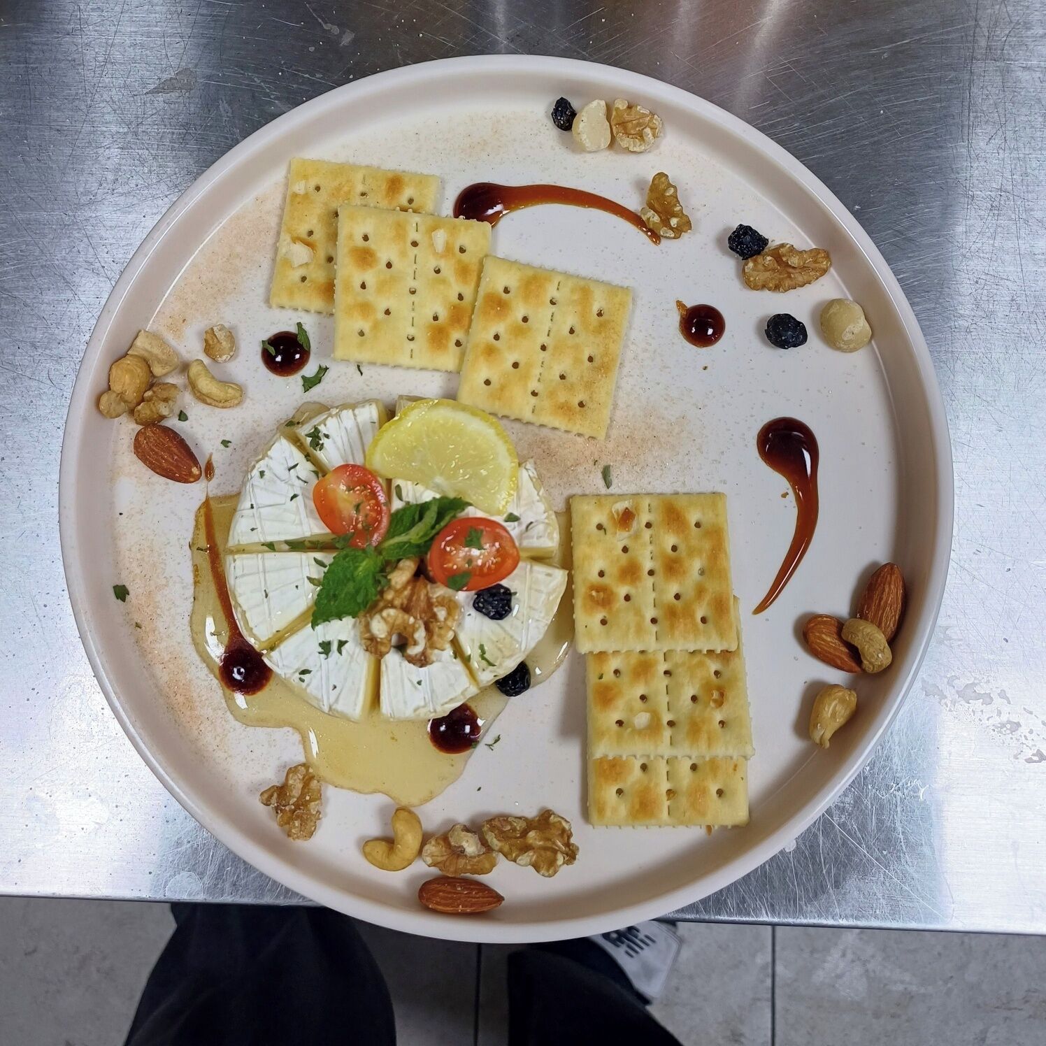 A plate with various food items including cheese, crackers, nuts, and a drizzle of sauce.