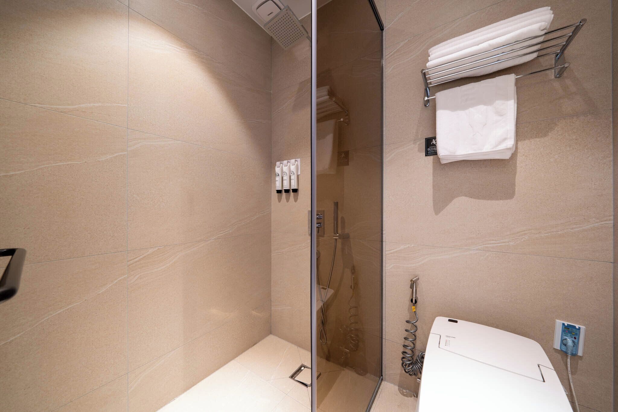 Un bagno moderno con box doccia in vetro, lavandino bianco e porta asciugamani con asciugni piegati.