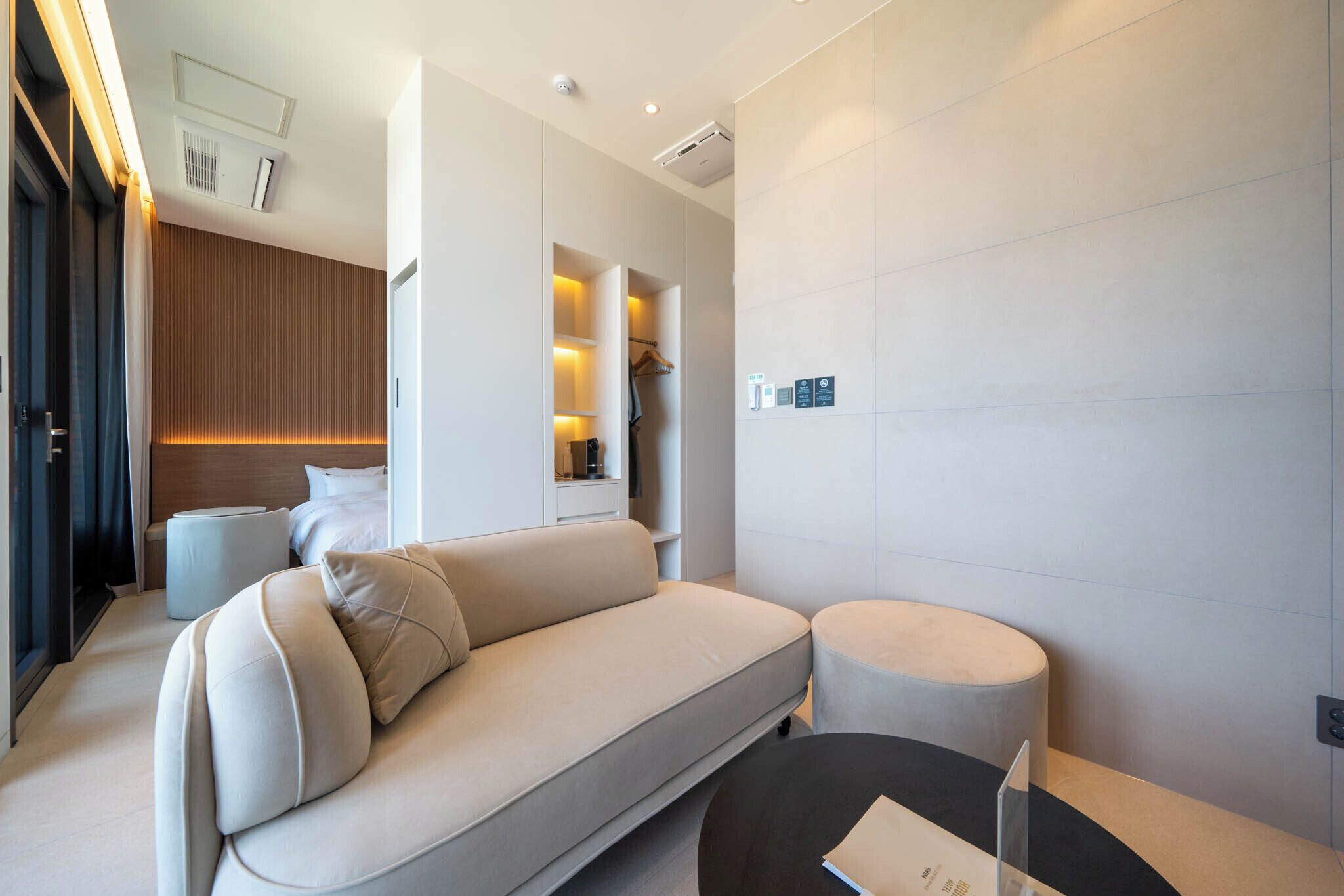 Une chambre d’hôtel moderne avec un canapé, un pouf et une petite table.