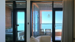 A hotel room with a sliding glass door leading to a balcony with a view of the sea. - Hound Hotel Daecheon (Boryeong)