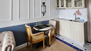 A kitchen with a dining table and chairs, wooden cabinets, and a hanging light fixture.