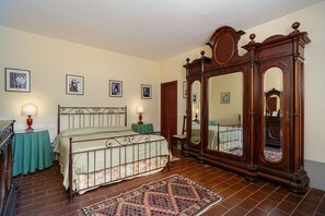 Classic design with a large wardrobe, striped bedding, and framed artwork adorns this room.