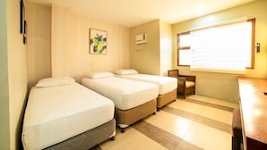 Camera d'albergo con due letti singoli, una piccola scrivania e una sedia.