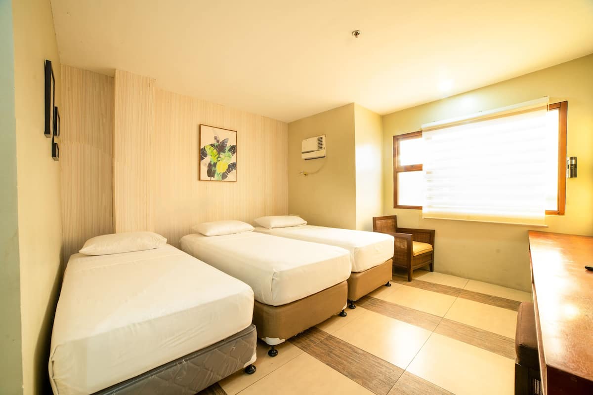 A hotel room with two single beds, a small desk, and a chair.