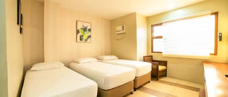 A hotel room with two single beds, a small desk, and a chair.