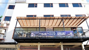Un hotel con un cartello che recita "LEVEL 007 HOTELS AND RESORTS, INC." e uno striscione pubblicitario per "Galaxy Milk Tea" con uno sconto del 30%.