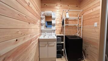 A compact wooden cabin bathroom with a sink, mirror, and shelves.