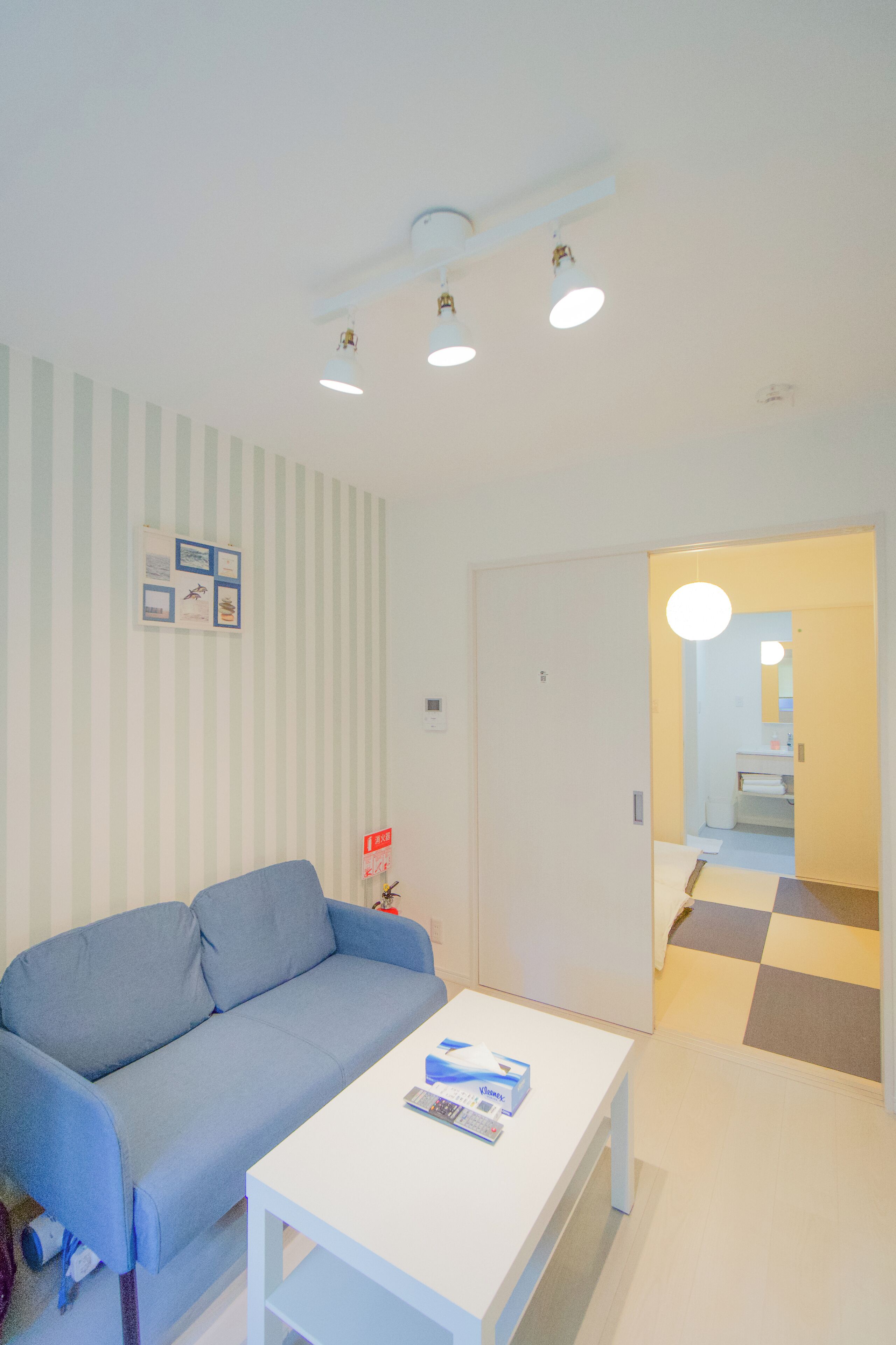 A modern living room with a blue sofa, a white coffee table, and a striped wall.