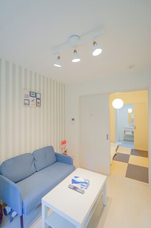 Un soggiorno moderno con un divano blu, un tavolino bianco e una parete a righe.