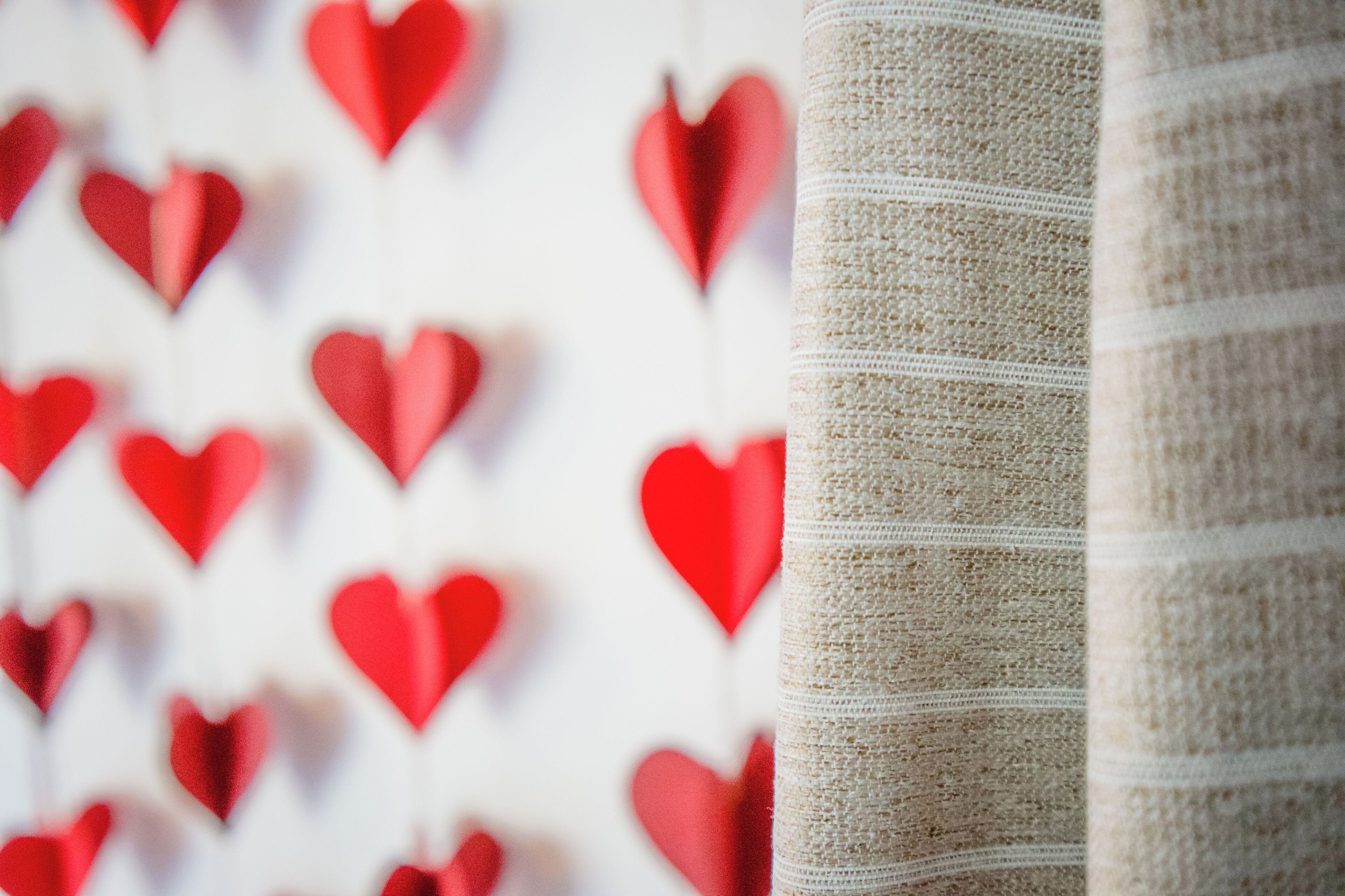 A close-up of a textured fabric with a pattern of red heart shapes.
