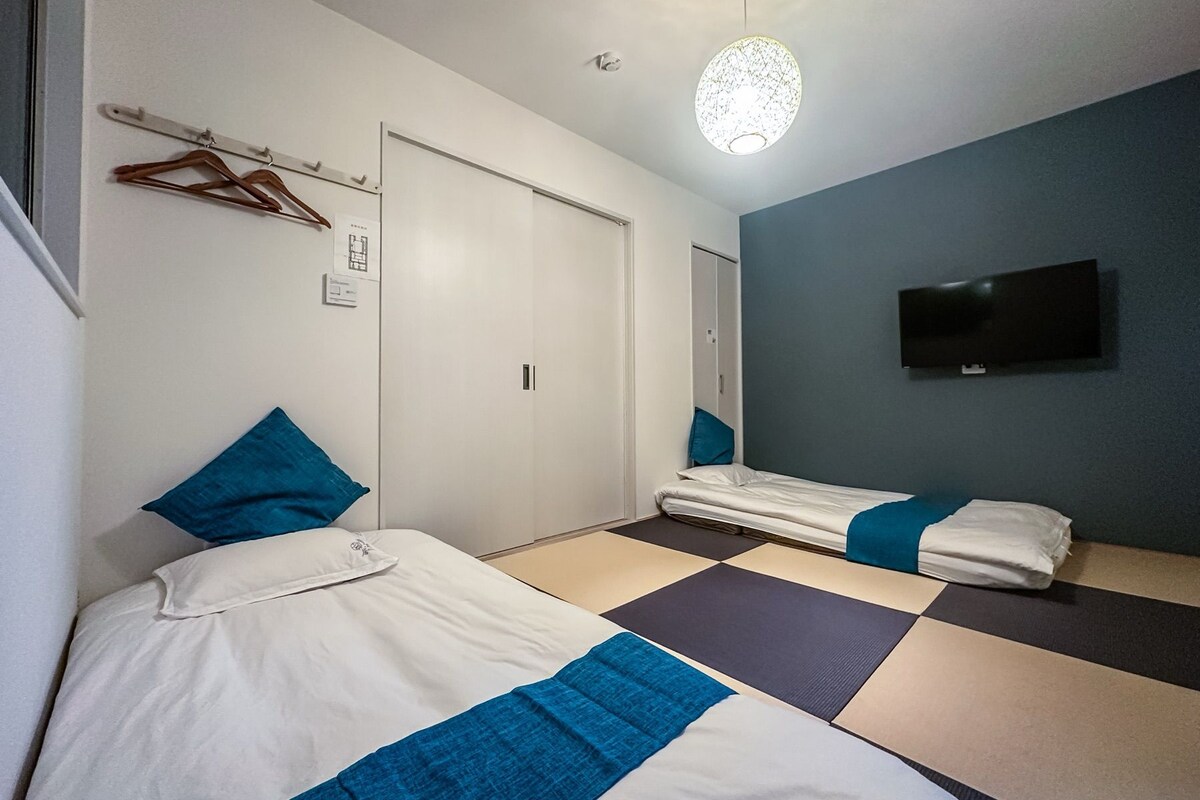 A hotel room with a bed, a TV mounted on the wall, and a ceiling light fixture.