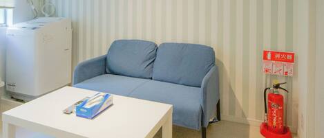 Ein Wohnzimmer mit einem weißen Sofa, einem weißen Couchtisch und einem roten Feuerlöscher.