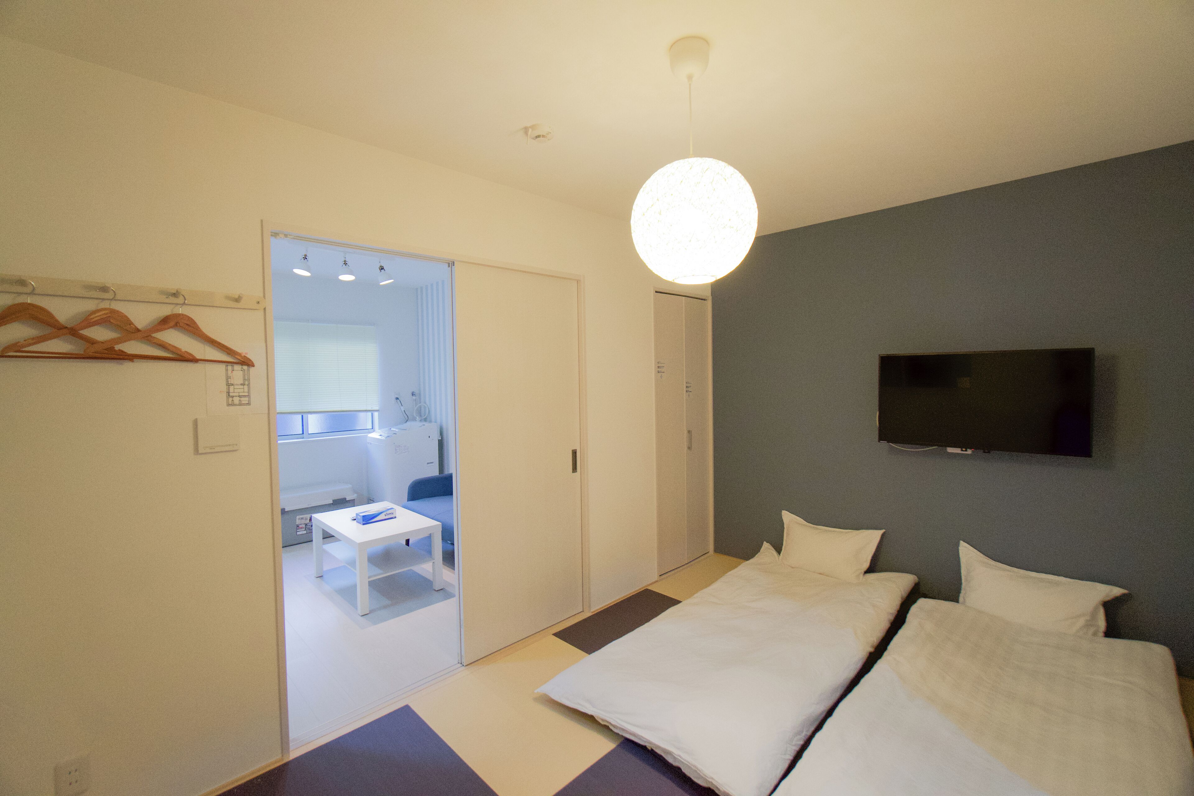 A modern bedroom with a bed, a TV mounted on the wall, and a door leading to a bathroom.