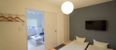 A modern bedroom with a bed, a TV mounted on the wall, and a door leading to a bathroom.