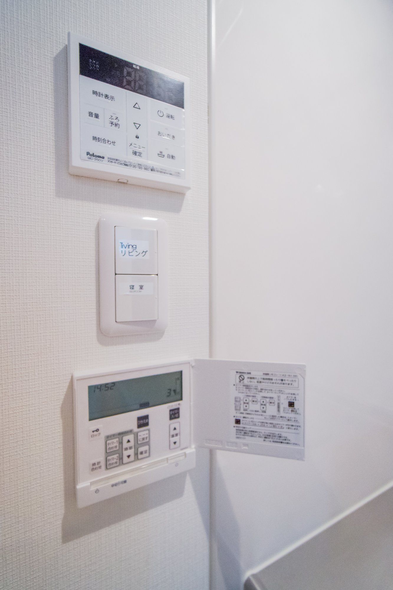 A thermostat and a control panel on a wall.