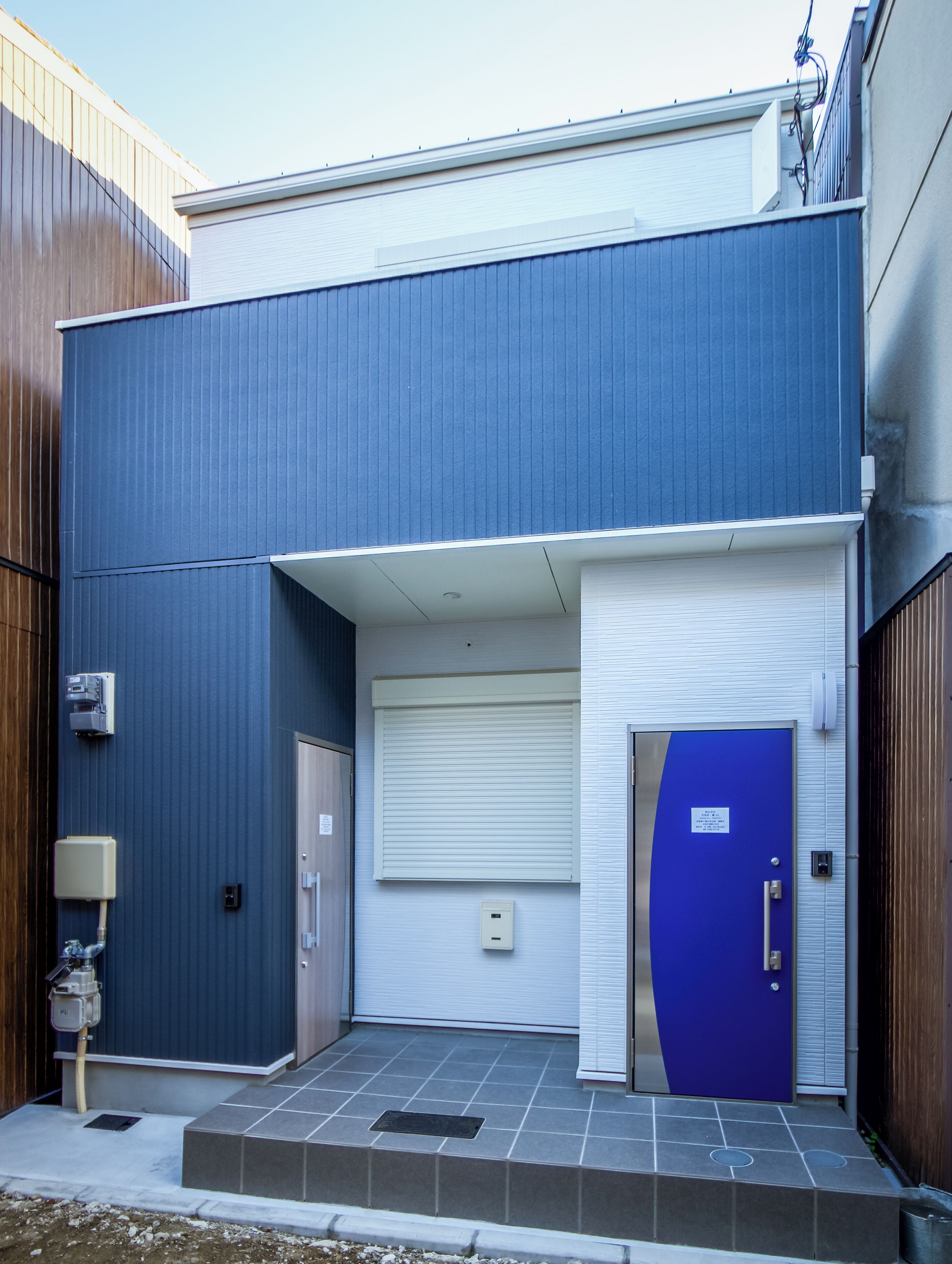 A building with a blue exterior, a white garage door, and a blue door.