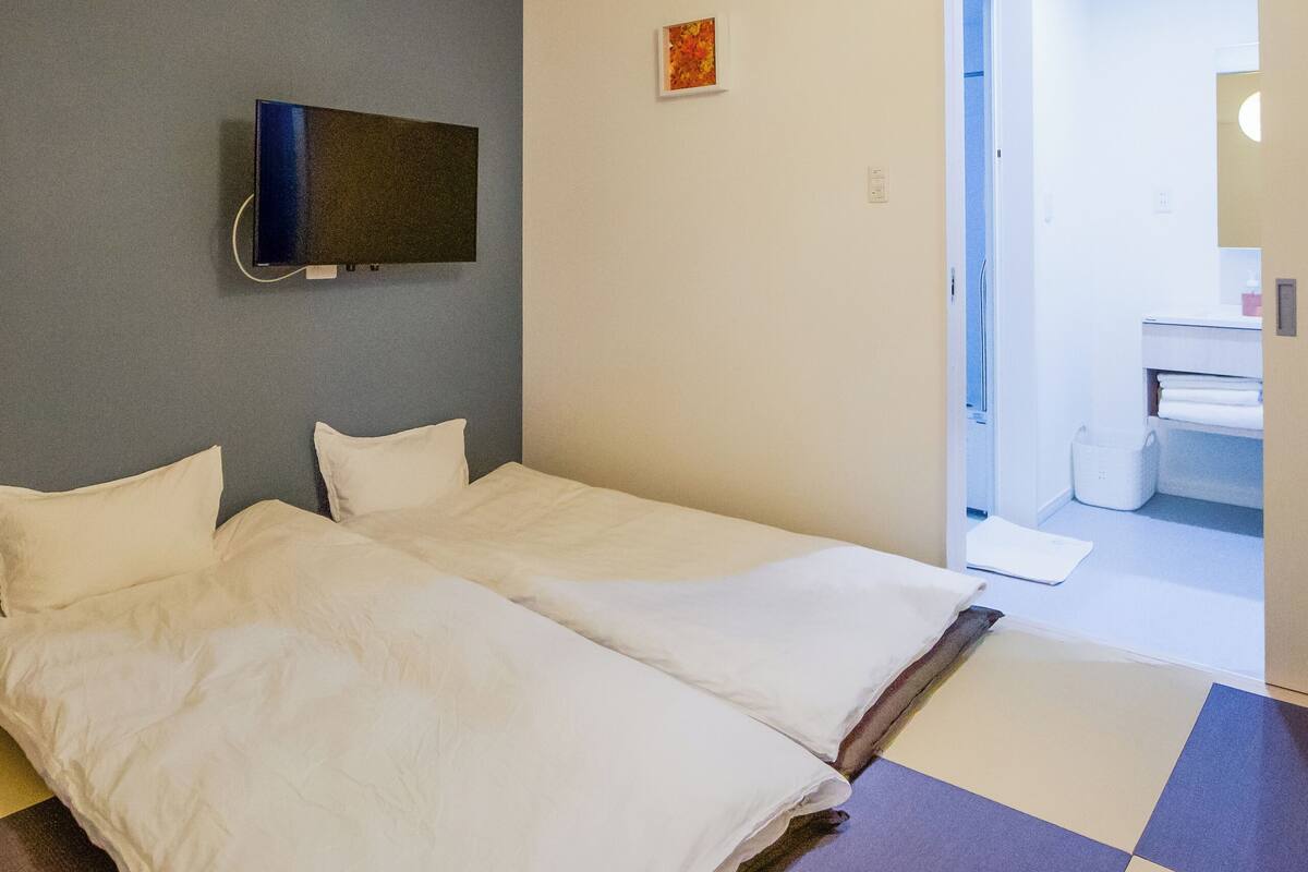 Una habitación con dos camas, un televisor de pantalla plana montado en la pared y suelo a cuadros.