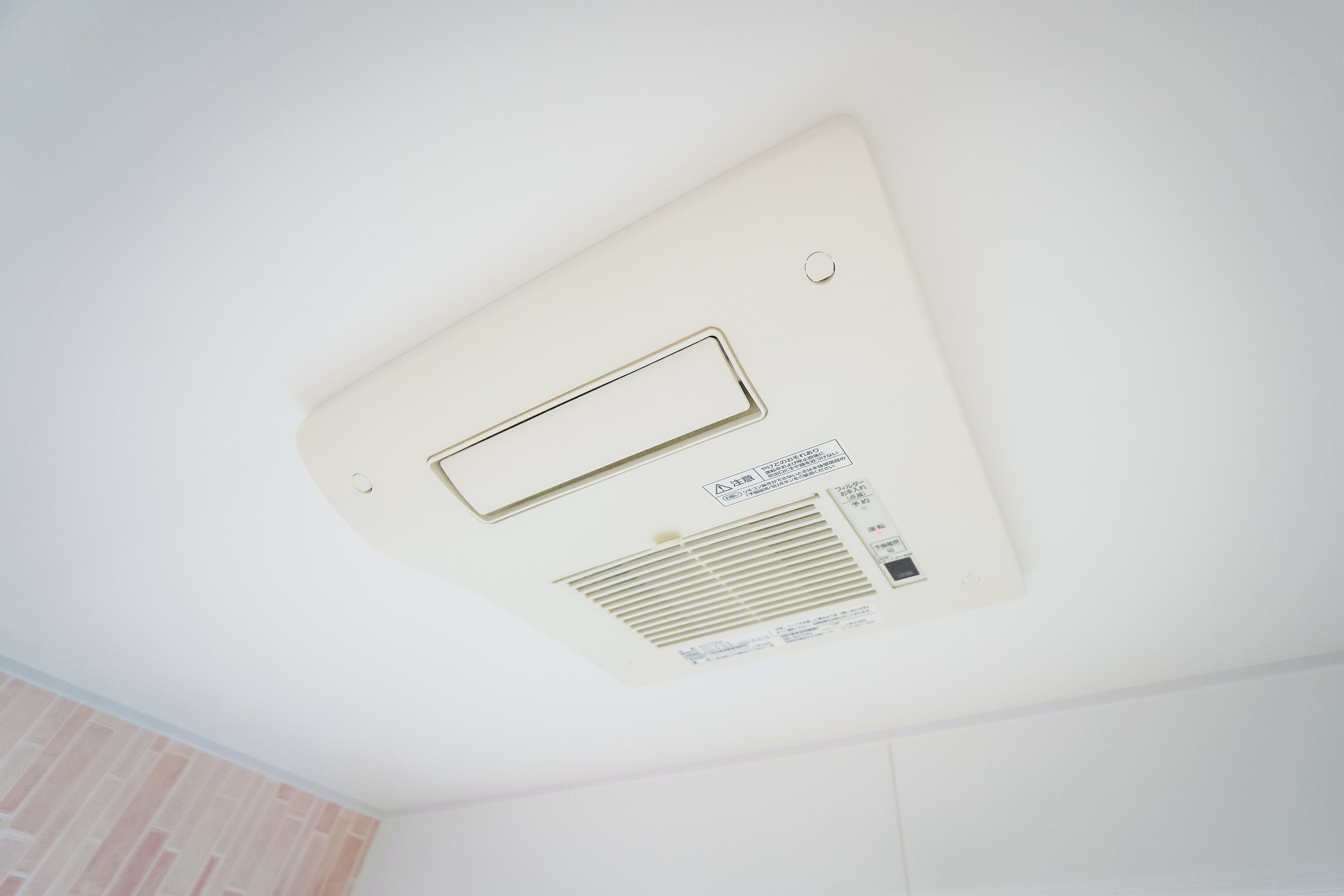 A ceiling with a ventilation unit and a control panel.