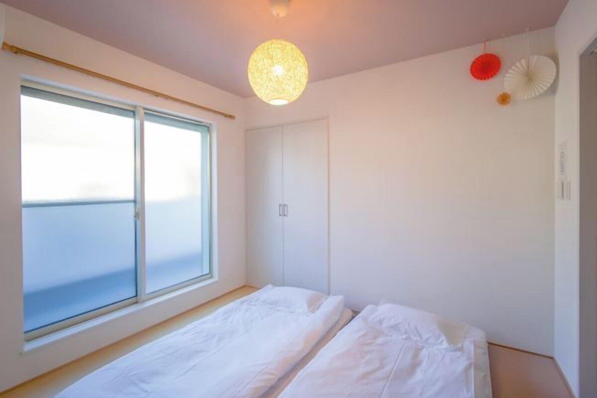 A bedroom with a large window, a bed, and a wardrobe.