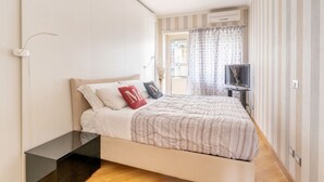 Une chambre à coucher avec un lit, une table de chevet, une télévision et des rideaux.