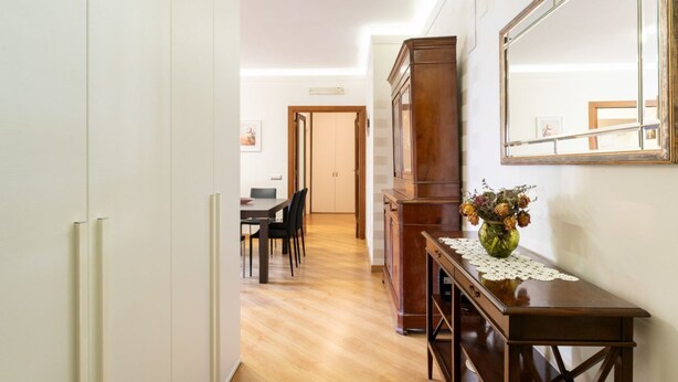 Un couloir comprenant un coin repas, une haute armoire en bois et un miroir accroché au mur.