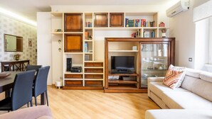 Un salon équipé d’un téléviseur, de meubles en bois, d’un canapé et d’un coin repas.