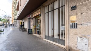 Un bâtiment avec une enseigne indiquant « PIZZA AL TAGLIO » et une grille métallique.