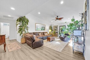 Relax in this stylish living room with a leather sofa, coffee table, and side table, surrounded by framed artwork and lush greenery.