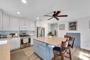 Enjoy cooking in this well-equipped kitchen with a central island, stainless steel appliances, and a ceiling fan.