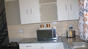 Une cuisine avec des meubles blancs, un four à micro-ondes, un grille-pain et une cuisinière.