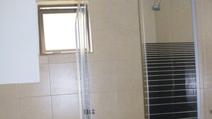 Une salle de bain comprenant des toilettes, un espace douche et une petite fenêtre.