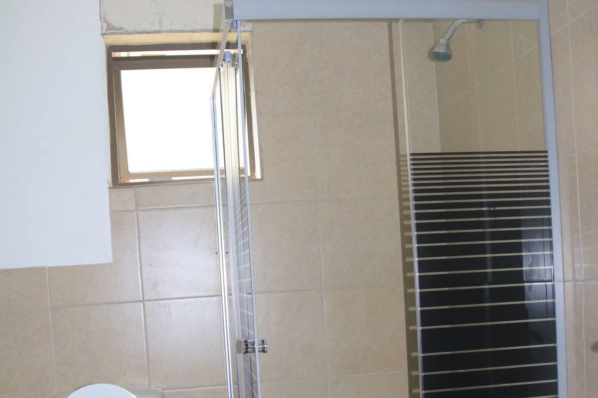Une salle de bain comprenant des toilettes, un espace douche et une petite fenêtre.