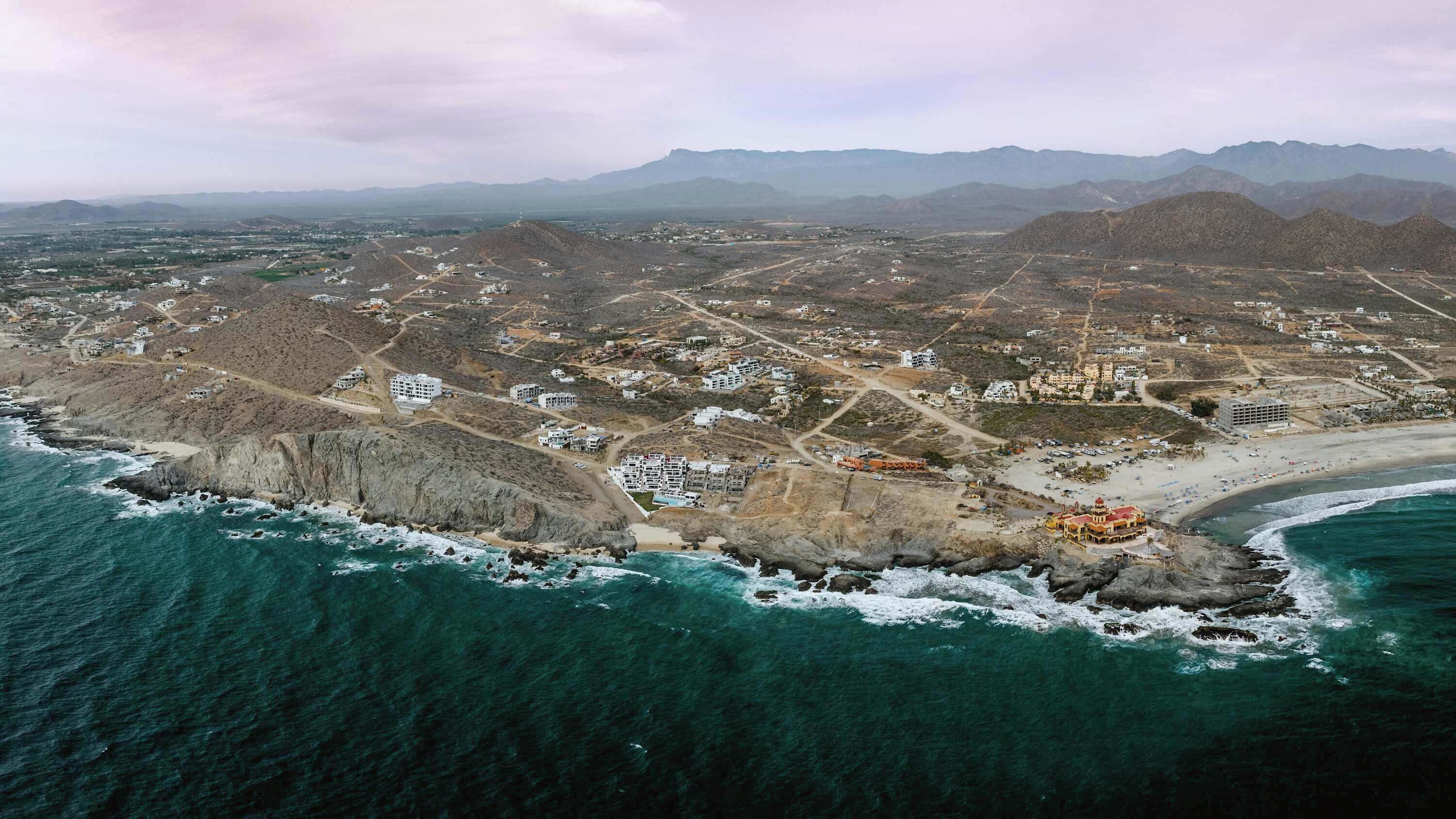 An aerial view of a coastal town with buildings, roads, and a beach.