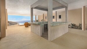 Un interno moderno con una zona bar centrale, ampie colonne e vista sull'oceano.