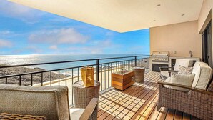 Un balcone con mobili in vimini, un barbecue e vista sull'oceano.