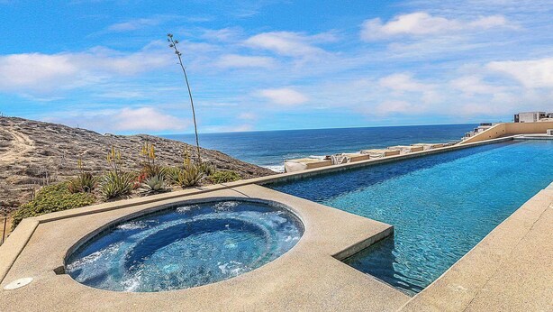 Una piscina a sfioro con idromassaggio, con vista su una spiaggia e l'oceano.