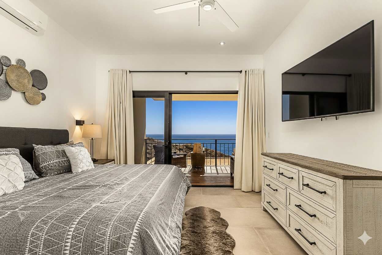 Une chambre avec un lit, une télévision, une commode et un balcon donnant sur la mer.