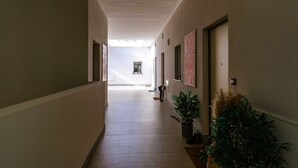 A corridor with a tiled floor, potted plants, and framed artwork on the walls. - GuestHost - Casa Cabiria Apartment (Torino)