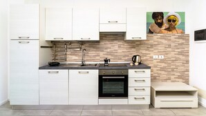 A modern kitchen with white cabinets, a black oven, and a tiled backsplash. - GuestHost - Casa Cabiria Apartment (Torino)