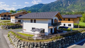 A modern chalet with a balcony, stone wall, and a view of mountains. - Beautiful chalet near the Nassfeld skiing area (Obermöschach)