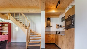 A modern kitchen with wooden cabinets, a built-in microwave, and a wooden staircase. - Beautiful chalet near the Nassfeld skiing area (Obermöschach)