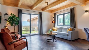 Un soggiorno moderno con soffitto in legno, un divano grigio, una poltrona in pelle marrone e un tavolino in legno.