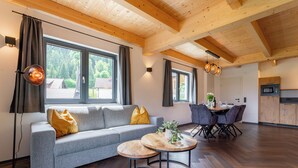 Un soggiorno moderno con un divano grigio, un tavolino in legno e un'area pranzo con sedie.